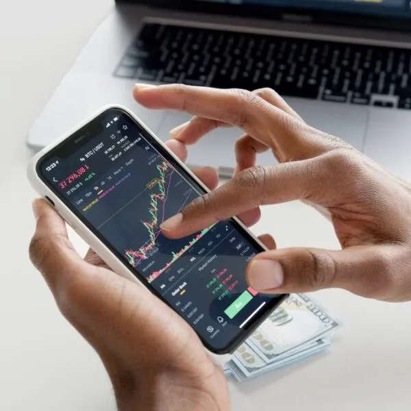 Mani che tengono uno smartphone con un’app di trading